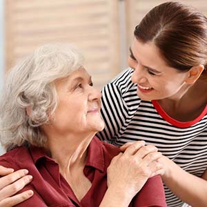 A younger adult with their arm wrapped around an older adult.